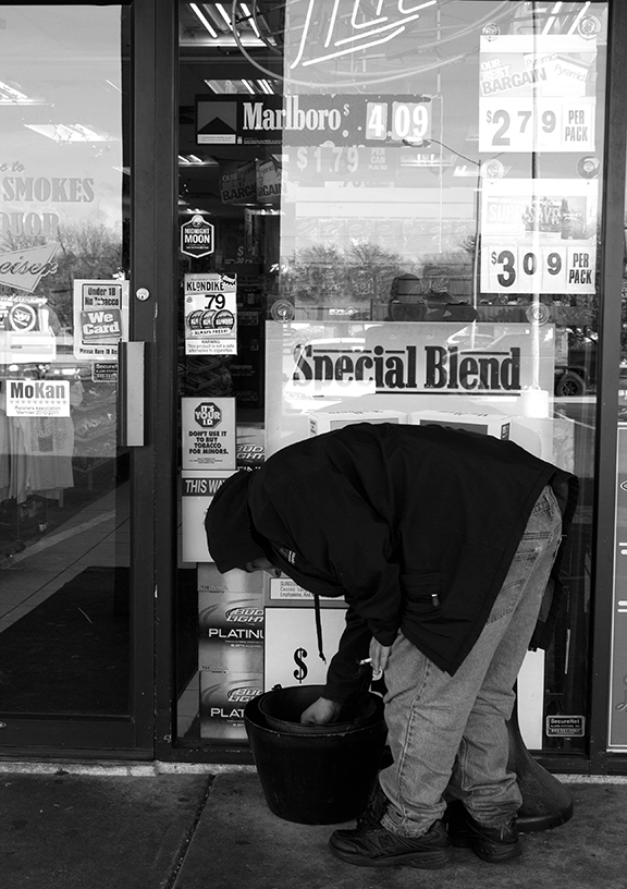 (Photo by Kristin Gallagher, digitalBURG) Preferring to use his nickname, Teddy Bear fishes for cigarettes in an ash can. Teddy is homeless but is working to help bring a permanent shelter to town.