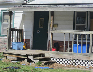 (Photo by Cliff Adams) A large hole is visible in the front door of a residence at 406 9th Street Terrace following an exchange of gunfire during an overnight police raid.