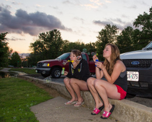 (Photo by Andrew Mather, digitalBURG) UCM seniors and roommates Liana Sharp (left), a commercial photography major, and Carrie Hall, a psychology major, take a break from their daily responsibilities to enjoy the beautiful weather at Lions Lake on Thursday evening. Liana and Carrie embrace their inner child as they blow bubbles while watching the sunset over the lake.