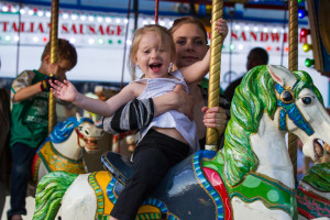 Liberty Isabel enjoys a fun ride on the merry-go-round as her mother, Valarie, keeps hold of her. Both are from Raytown. Valarie enjoys taking her daughter to the festival and has been coming to the Downtown Days for many years before her daughter was born.