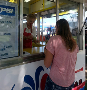 (Photo by Alexandra Lambdin, digitalBURG) Barbra Peck hands a corndog to customer a corndog after smothering it in ketchup.