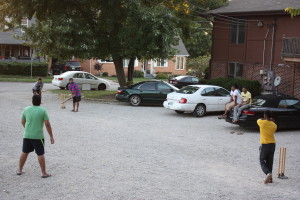 PHOTO BY TYRAN BROOKS FOR THE MULESKINNER Srni Srinivas (right) prepares to bowl in a backyard cricket match with his roommates in his apartment complex’s gravel driveway.