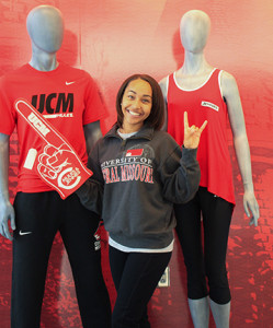 PHOTO BY BETHANY SHERROW / ASSISTANT NEWS EDITOR Sierra Seals works at the new University Store. She stands next to some mannequins and wears a Mules and Jennies foam finger to show her UCM pride.