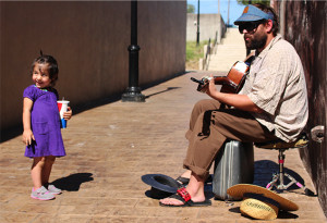 Photos by Cliff Adams/digitalBURG Jesse Jones, of Warrensburg, plays guitar Saturday during Burg Fest while Ona, 2, ensures her mother is watching. Burg Fest is an annual family-friendly event in downtown Warrensburg, Missouri.