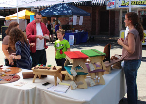Three Trees Workshop co-owner Cynthia Epp engages with patrons at her booth Saturday during Burg Fest in downtown Warrensburg. Three Trees Workshop specializes in wooden games, toys and household items. 