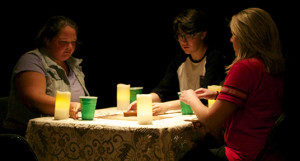 From left, Caitlin Hahn as Devon, Ahafia Jurkiewicz-Miles as Ben and Michelle Boyer as Lara, portray three teenagers playing with a Ouija board in an abandoned storage room Friday night in the Black Box Theatre as part of the Studio One-Act play “Dead Boy.”