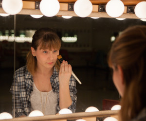 PHOTO BY BRANDON BOWMAN / PHOTO EDITOR Leah Eggimann demonstrates how an actress/actor would apply stage makeup Tuesday afternoon in the dressing room behind the Highlander Theatre.