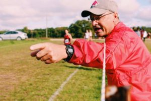 OHOT BY KATIE CASSIDY/PHOTOGRAPHER Coach Kirk Pedersen shouts for his athlete, junior Jami Clay, to move at a recent cross-country invitational in Kansas.